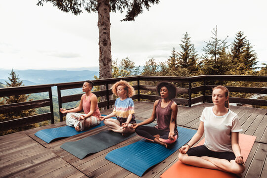 Group of women meditating on mountain deck