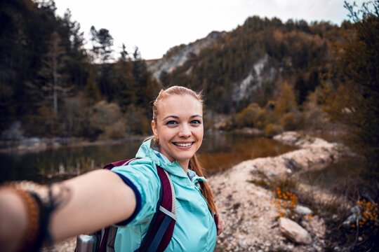 Smiling female hiker taking selfie by mountain lake