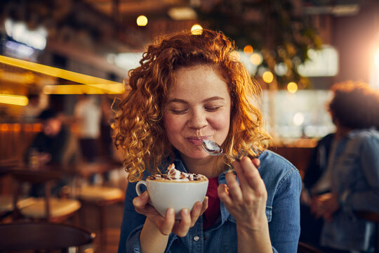 Young woman enjoying coffee in cozy cafe
