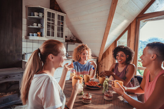 Four friends enjoying healthy breakfast in mountain cabin kitchen