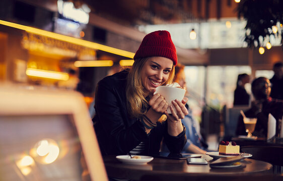 Smiling woman enjoying hot drink in cozy cafe