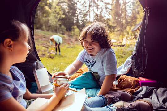 Happy children drawing in a tent at forest campsite