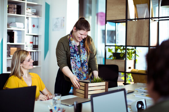 Coworkers welcoming new hire setting up desk in modern office