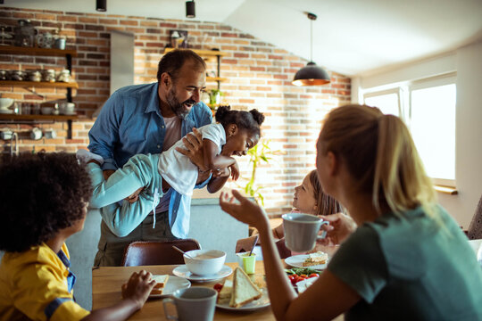 Parents and children enjoying a playful breakfast in a home kitchen