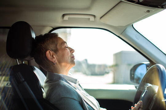 Mature woman resting in driver's seat of parked car