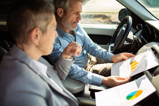 Two business colleagues reviewing charts in a car
