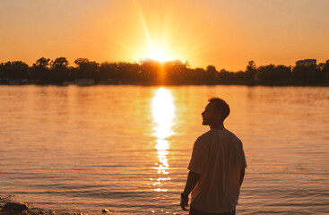 Fototapeta premium Man Enjoying Golden Sunset By River