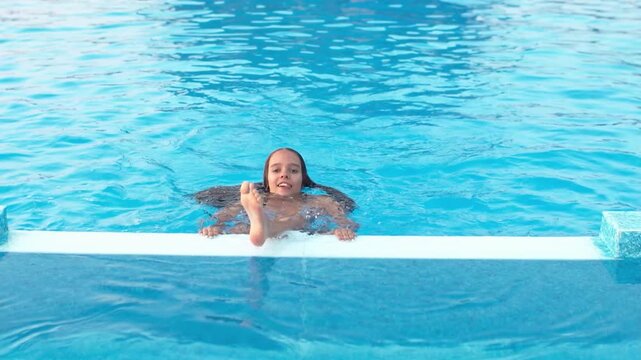 Girl in leopard swimsuit playing in the pool under the summer sun