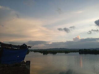 Obraz premium Fishing Rods at Dawn Over Calm River with Dramatic Cloudscape and Reflections