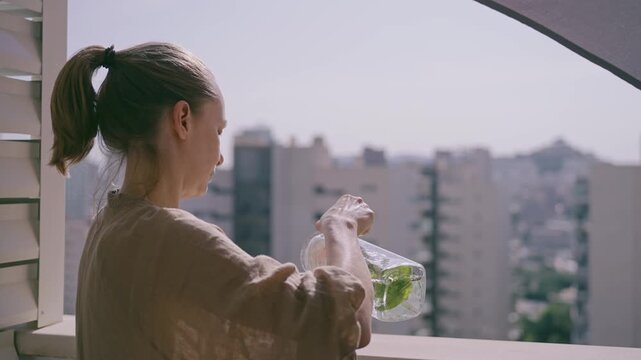 A person stands on a balcony in Benidorm holding a jar of fresh herbs. The sun shines brightly as they prepare to enjoy the herbs in their meal or drink