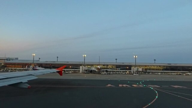 2026年4月、成田国際空港にて、タキシング中の機内窓から見える誘導路と空港ターミナルビルの景色