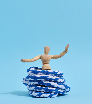A wooden mannequin with raised arms is released from a trap shaped like a skein of blue and white rope a