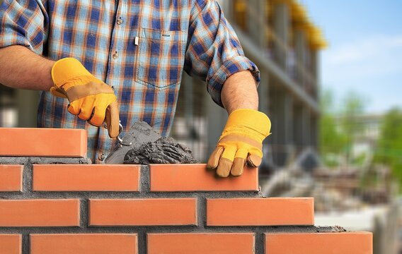 Construction workers building walls with brick blocks.