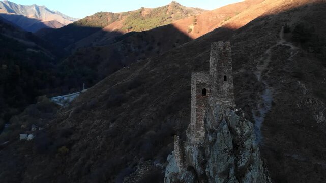 Ancient stone watchtower ruin on a rugged mountain ridge at sunset . Media