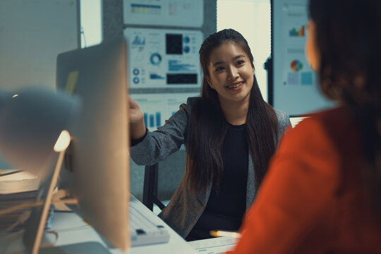 Business executive discussing progress reports and analytics with colleague during late hours, working proactively on a corporate project