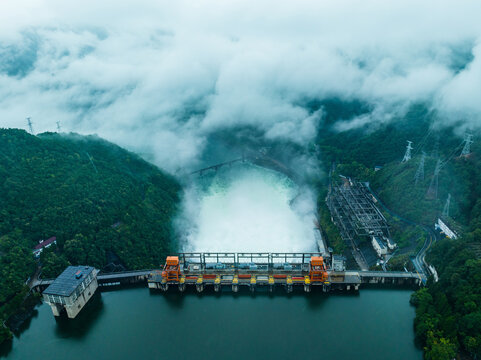 Aerial view of hydroelectric dam release in misty mountain valley