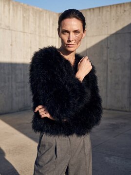 High fashion outdoor portrait of woman in black faux fur jacket and tailored trousers for editorial lookbook and seasonal campaign background