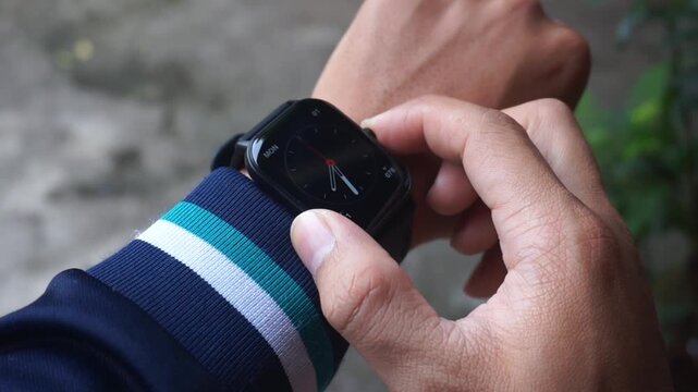Close up of a hand touching a smartwatch.
