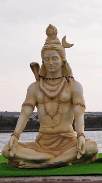 Closeup of lord shiva statue with flowing river background