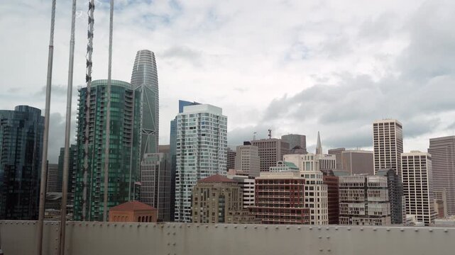 Unique city view of the san francisco downtown skyline while driving on the iconic oakland bay bridge, showing famous landmarks like the salesforce tower on a cloudy day in california
