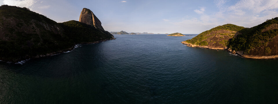Aerial view of Sugarloaf Mountain and Guanabara Bay with lush green hills and calm blue waters under a clear sky Rio de Janeiro, State of Rio de Janeiro, Brazil.