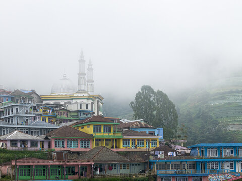 Aerial view of Nepal Van Java with colorful houses and a mosque shrouded in thick morning mist in Kecamatan Kaliangkrik, Jawa Tengah, Indonesia.