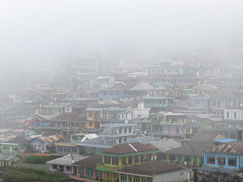 Aerial view of Nepal Van Java village with colorful houses nestled on a hillside under a thick layer of morning mist and fog Kecamatan Kaliangkrik, Jawa Tengah, Indonesia.