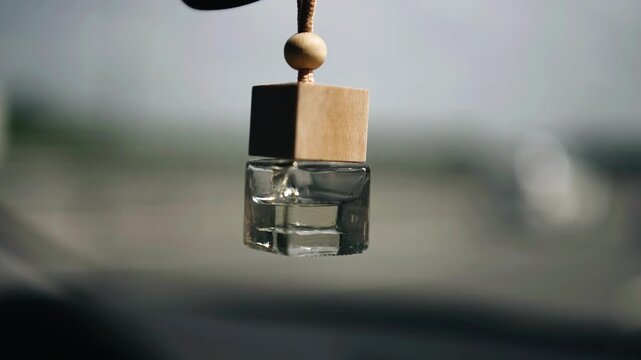 The air freshener keychain is hanging in the car next to the rearview mirror. The air freshener moves while riding