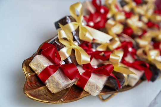 traditional brazilian bem casado wedding sweets on golden platter, wrapped party favors with red and gold ribbons, high angle view of artisanal confectionery desserts with copy space