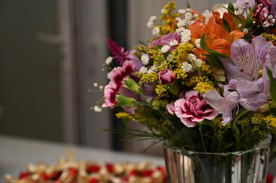 vibrant mix of flowers in crystal vase on festive table setup, beautiful floral arrangement bouquet with carnations and alstroemeria, close up selective focus of birthday center piece with copy space