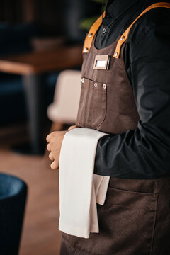 Professional waiter in apron holding service towel in restaurant ready for guests