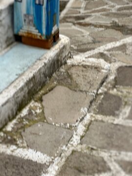 Steps lead to a blue building in a cobblestone path with white lines on a sunny day