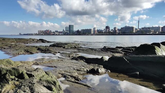 Wide lockdown shot scene video rocky coast and skyline at background in a sunny winter day in montevideo city, uruguay