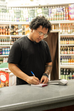 Small business owner writing order at store counter