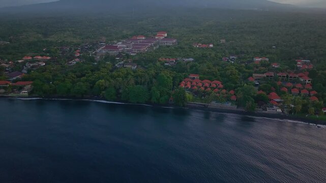 Aerial drone tilt up revealing Mount Agung volcano behind Tulamben coast, Bali at dusk