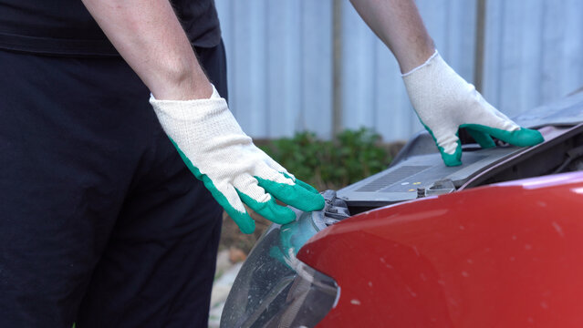 Person Performing Maintenance on a Car, Examining the Engine Compartment with Careful Attention and Protective Gloves for Safety