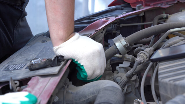 Detailed Mechanic Repair Work Under the Hood: A Close-Up of an Automotive Technician's Hand with a Glove Performing Maintenance on an Engine Component