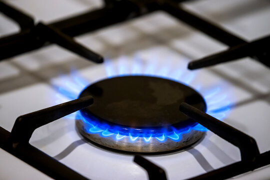 Close-up of a burning blue gas flame on a white kitchen stove top hob. kitchen cooking appliance, natural energy resources