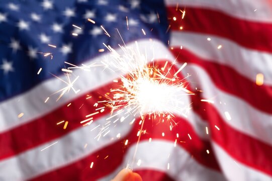 Hand holding a sparkler and American Flag