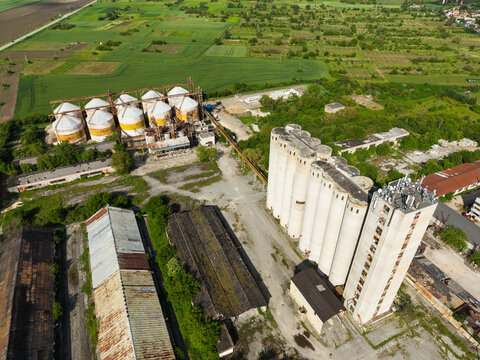 Aerial view of large industrial grain silos and storage facilities surrounded by green agricultural fields and rural landscape in Balchik, Dobrich Province, Bulgaria.