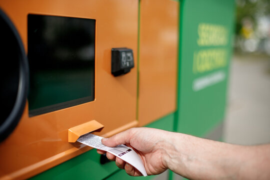 Man hand puts plastic bottle to the Recycling machine. Shoppers return their bottles and cans.kaucja
