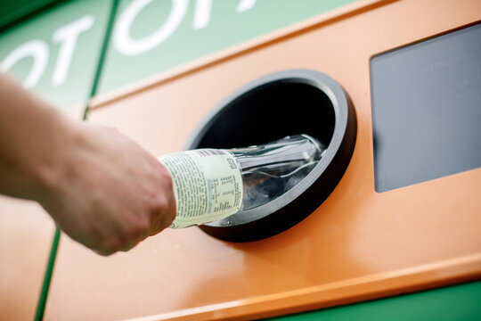 Man hand puts plastic bottle to the Recycling machine. Shoppers return their bottles and cans.kaucja