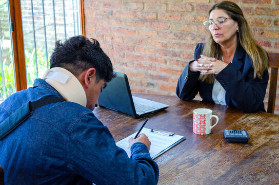Man victim of accident signing a document.Female mature adult lawyer assist a injured man with legal problem. Lawyer showing document. Compensation for work or car accident.