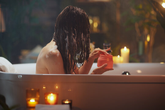 Woman Applying Hair Mask in a Cozy Candlelit Bath