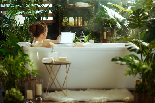 Woman Unwinding with Tablet in a Lush Spa Bath