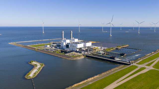 Aerial view of the ENGIE Maxima Power Plant and offshore wind turbines under a clear blue sky Lelystad, Flevoland, Netherlands.