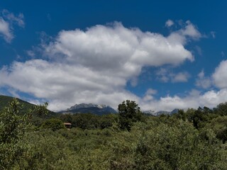 Fototapeta premium Wide view of green landscape with mountains and clouds during daytime in a rural area
