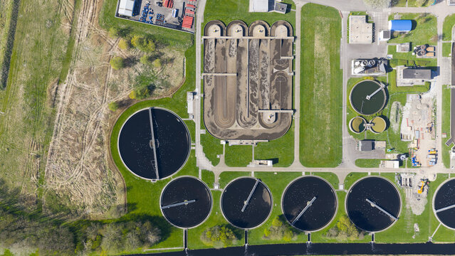 Aerial view of the RWZI - Geestmerambacht wastewater treatment plant with circular sedimentation tanks and aeration basins in Warmenhuizen, Noord-Holland, Netherlands.
