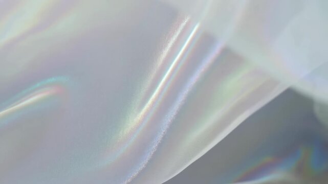 Static shot of iridescent holographic fabric shimmering and moving gently in the wind