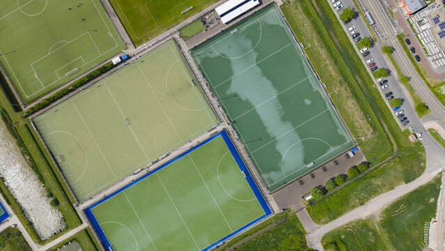 Aerial view of the hockey fields at H.C. Rijnvliet featuring green and blue artificial turf pitches and a nearby parking lot in Utrecht, Utrecht, Netherlands.